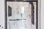 Step into luxury with this stunning shower featuring a sleek black shower panel and elegant marble-look tiles.
