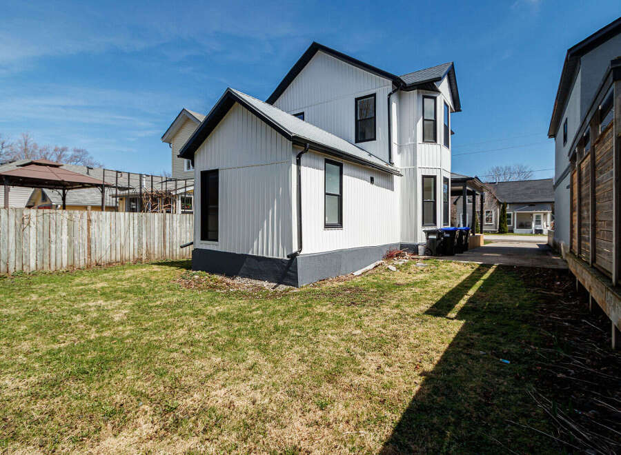 This charming property boasts a modern exterior with a fresh coat of white paint and contrasting black trim, creating a striking curb appeal.