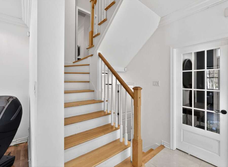 This stunning property boasts a beautifully designed staircase with natural wood steps and white risers, creating a bright and inviting entryway.