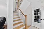 This stunning property boasts a beautifully designed staircase with natural wood steps and white risers, creating a bright and inviting entryway.