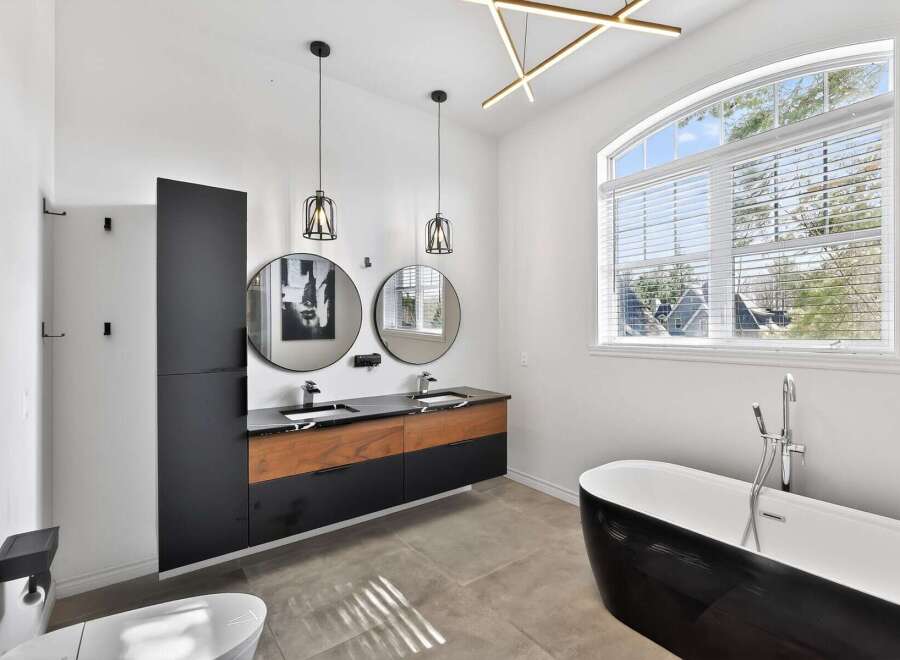 Step into luxury with this stunning bathroom! Featuring a sleek, modern design, this space boasts a double vanity with stylish round mirrors and pendant lighting.