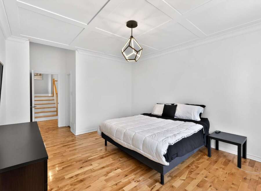 This stunning bedroom boasts a modern design with a geometric pendant light and a coffered ceiling, creating a sophisticated ambiance.
