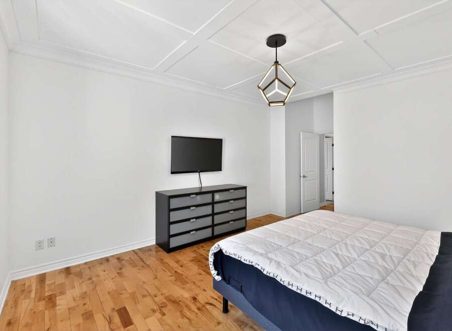 Step into this modern bedroom featuring a sleek, mounted TV and a stylish dresser.