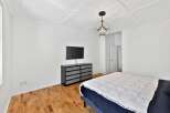 Step into this modern bedroom featuring a sleek, mounted TV and a stylish dresser.