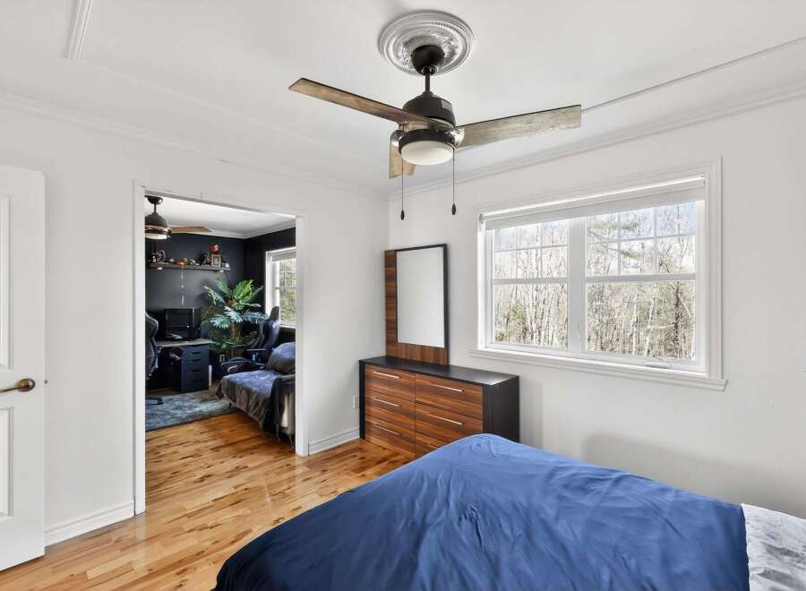 Discover the charm of this inviting bedroom, featuring a stylish ceiling fan and a well-appointed dresser.