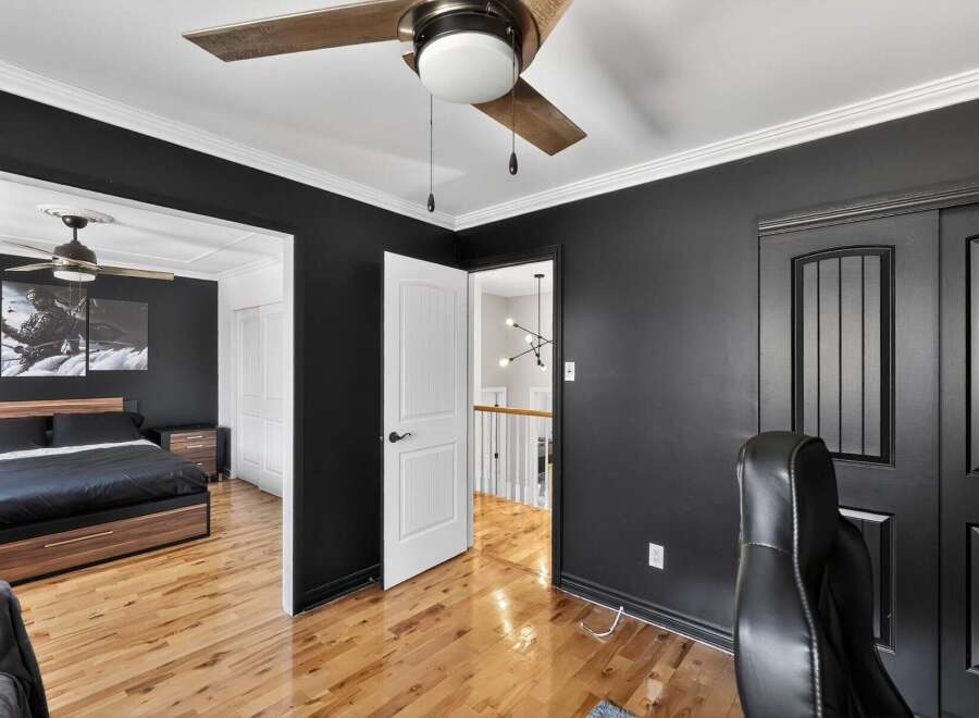 Step into this stylish bedroom featuring a modern design with sleek black walls and elegant white trim.