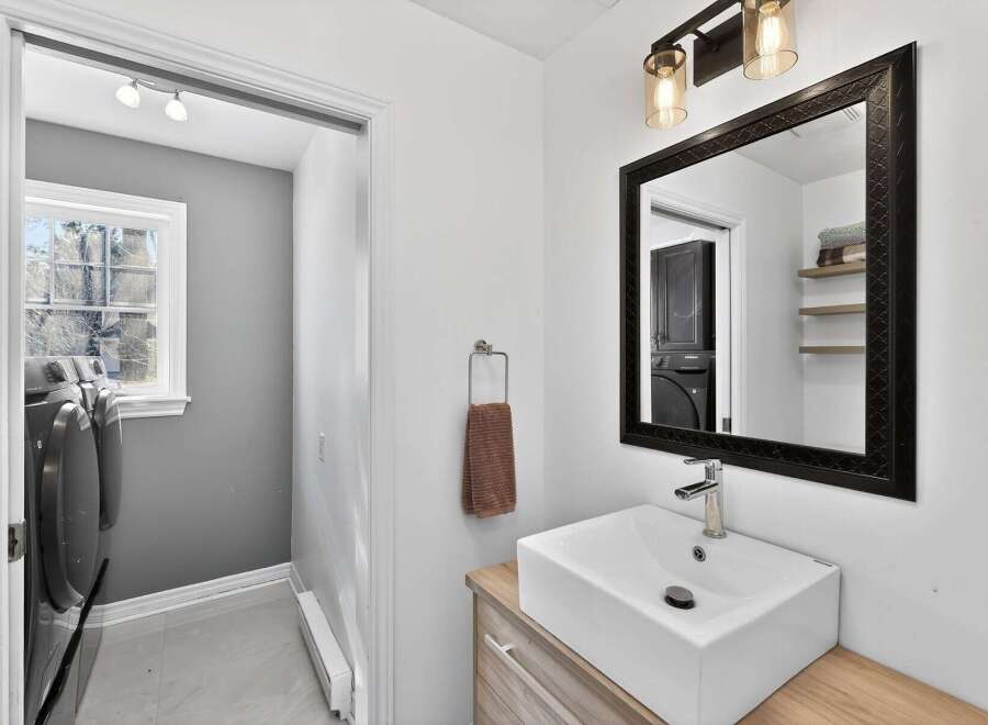 This stunning bathroom boasts a modern design with a sleek, white rectangular sink and a stylish black-framed mirror.