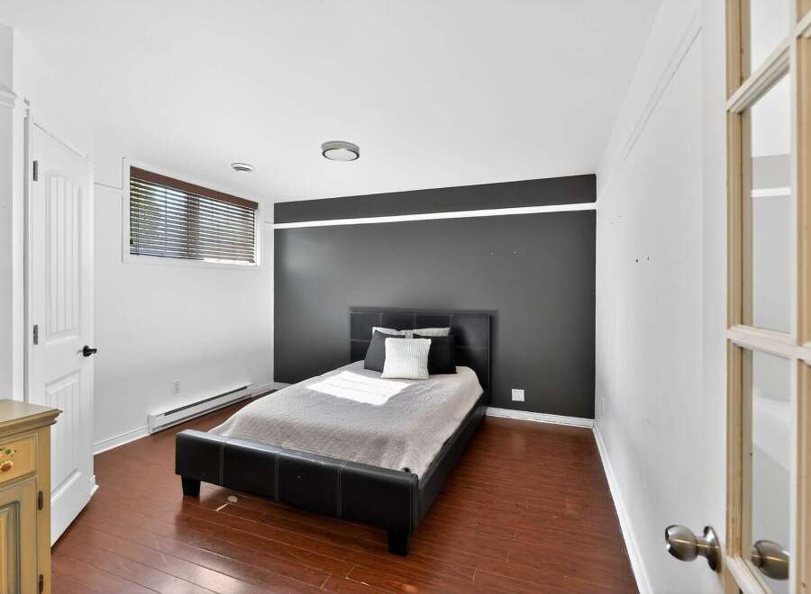 This stylish bedroom features a modern design with a sleek black bed frame and a contrasting dark accent wall.
