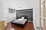 This stylish bedroom features a modern design with a sleek black bed frame and a contrasting dark accent wall.
