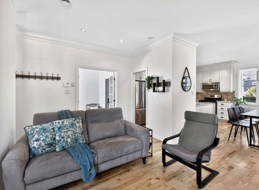 Step into this inviting living space, featuring a comfortable gray sofa adorned with floral pillows and a cozy blue throw.