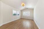 This bright and airy room features beautiful hardwood floors and a vaulted ceiling, creating a spacious and inviting atmosphere.