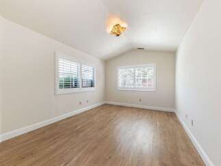 This bright and airy room features beautiful hardwood floors and a vaulted ceiling, creating a spacious and inviting atmosphere.