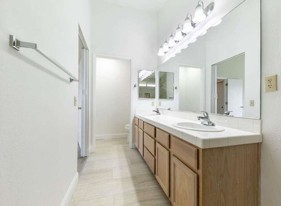 This bright and airy bathroom features a dual-sink vanity with ample storage.