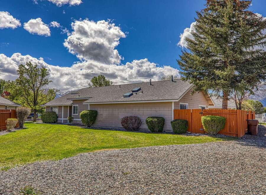 This charming property boasts a well-maintained exterior with a lush green lawn and a gravel driveway.