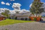 This charming property boasts a well-maintained exterior with a lush green lawn and a gravel driveway.