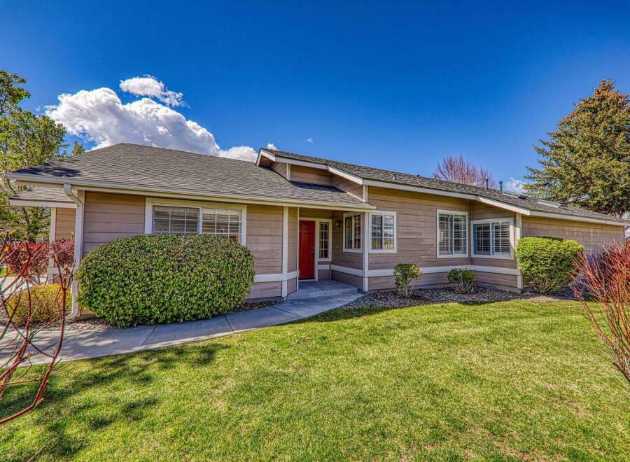 This charming home boasts a welcoming red front door and a well-maintained exterior.