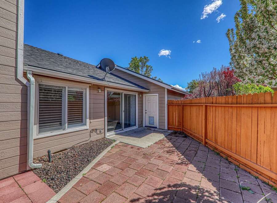Enjoy outdoor living in this charming patio space! Featuring a brick patio, a wooden fence, and a sliding glass door, this area is perfect for relaxation and entertaining.