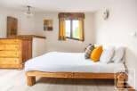 Discover the charm of this cozy bedroom, featuring a rustic wooden bed frame and a bright, airy atmosphere.