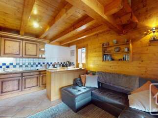 This charming property boasts a warm and inviting interior, featuring a cozy living space with a comfortable leather sofa.