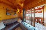 Experience the warmth of this cozy cabin with its inviting wooden interior and stunning balcony views.