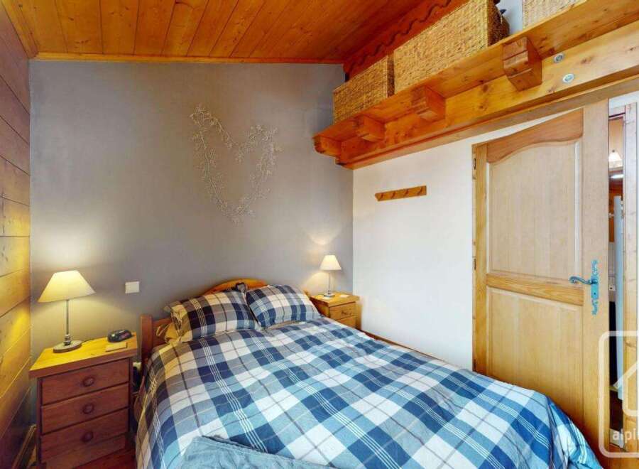Discover the charm of this cozy bedroom, featuring a comfortable bed with a stylish blue and white plaid comforter.