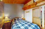 Discover the charm of this cozy bedroom, featuring a comfortable bed with a stylish blue and white plaid comforter.