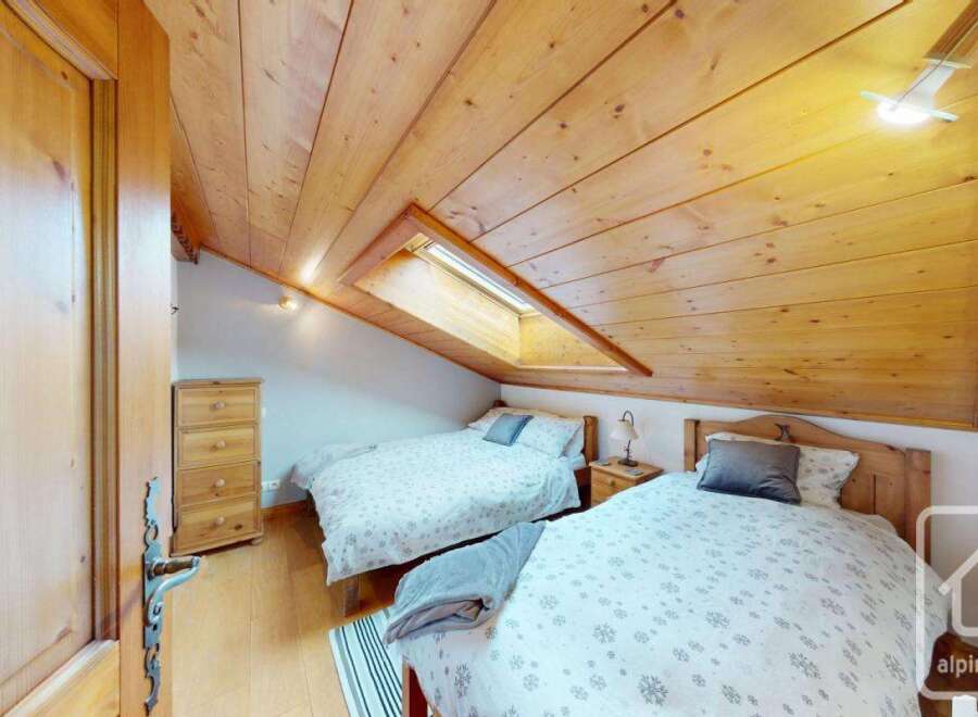 Discover this charming bedroom featuring a unique sloped ceiling with a skylight, creating a cozy and inviting atmosphere.