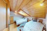 Discover this charming bedroom featuring a unique sloped ceiling with a skylight, creating a cozy and inviting atmosphere.