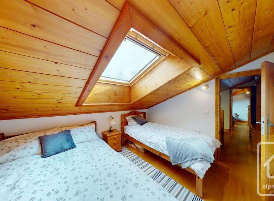 This charming bedroom features a cozy, wooden-paneled ceiling and a skylight that floods the space with natural light.