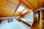 This charming bedroom features a cozy, wooden-paneled ceiling and a skylight that floods the space with natural light.