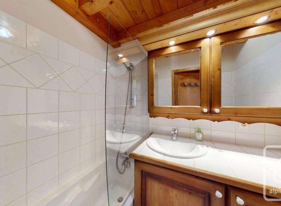 Discover the charm of this beautifully designed bathroom, featuring a stylish wooden vanity and a modern shower enclosure.