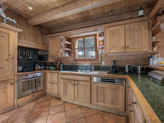 This charming kitchen boasts a rustic, inviting atmosphere with its wooden cabinetry and exposed beams.