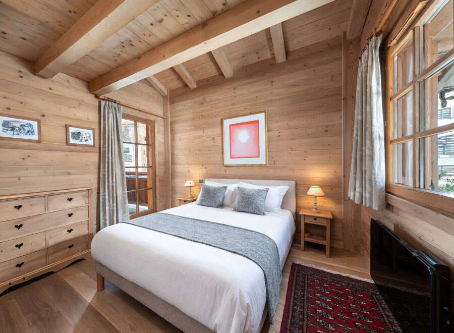 Experience the warmth and charm of this cozy bedroom, featuring stunning wood paneling and a rustic aesthetic.