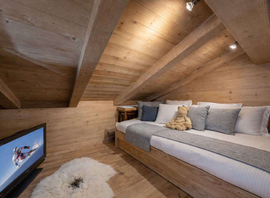 This cozy attic bedroom features a warm wooden interior, creating a rustic and inviting atmosphere.