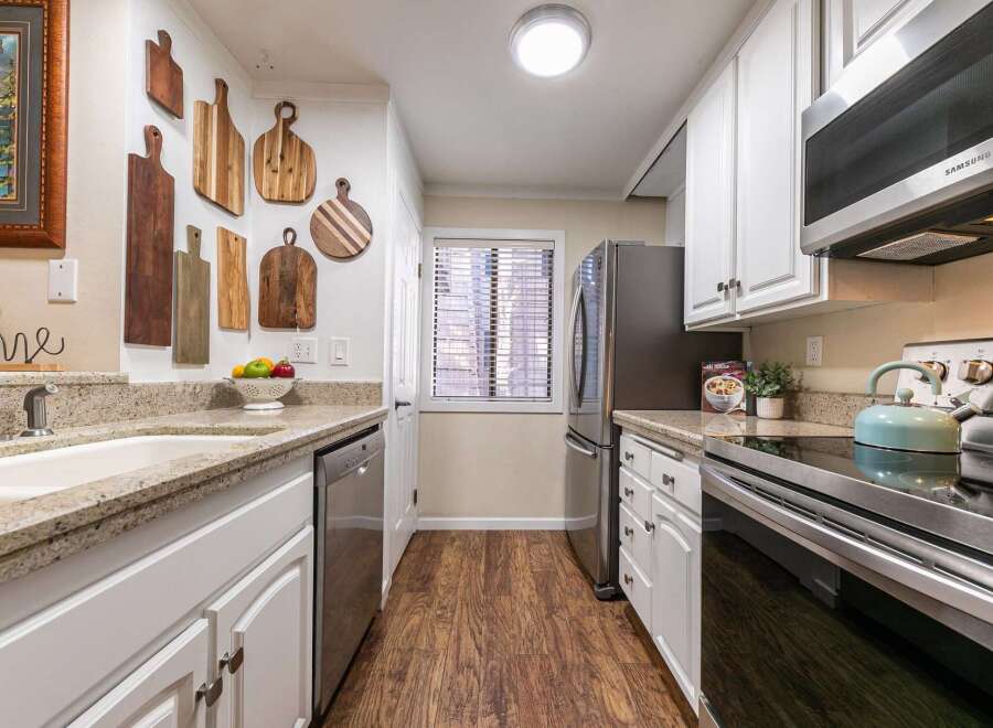 This charming kitchen boasts a stylish design with its white cabinetry and granite countertops.