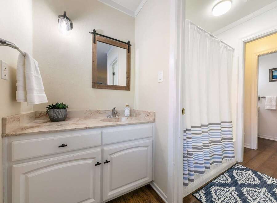 This charming bathroom features a stylish vanity with ample storage, a beautiful mirror, and a modern light fixture.