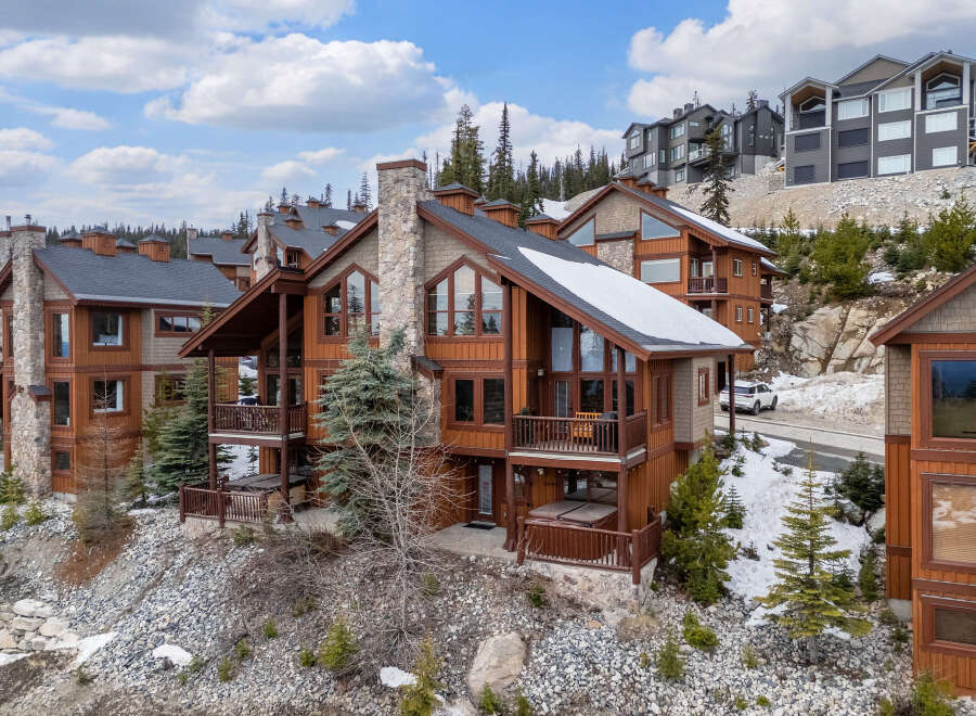Discover luxury living in this stunning mountain home! This property boasts a beautiful exterior with a stone chimney, wooden balconies, and a hot tub.