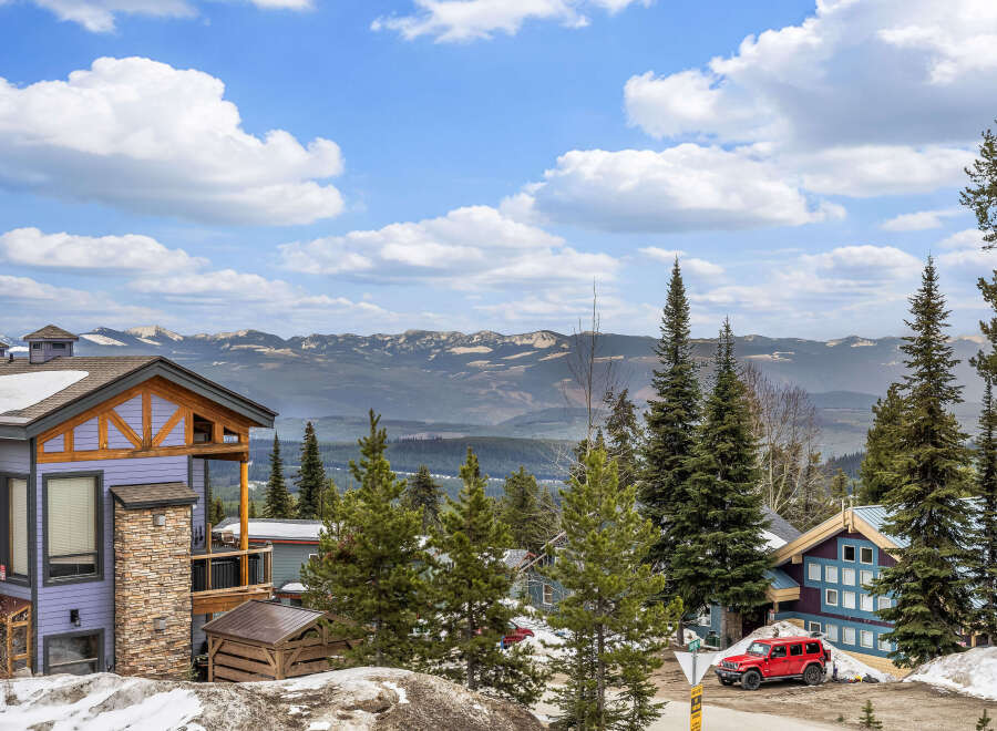 Discover your dream mountain retreat! This stunning property boasts a beautiful exterior with a vibrant color palette and is surrounded by lush greenery and majestic mountain views.