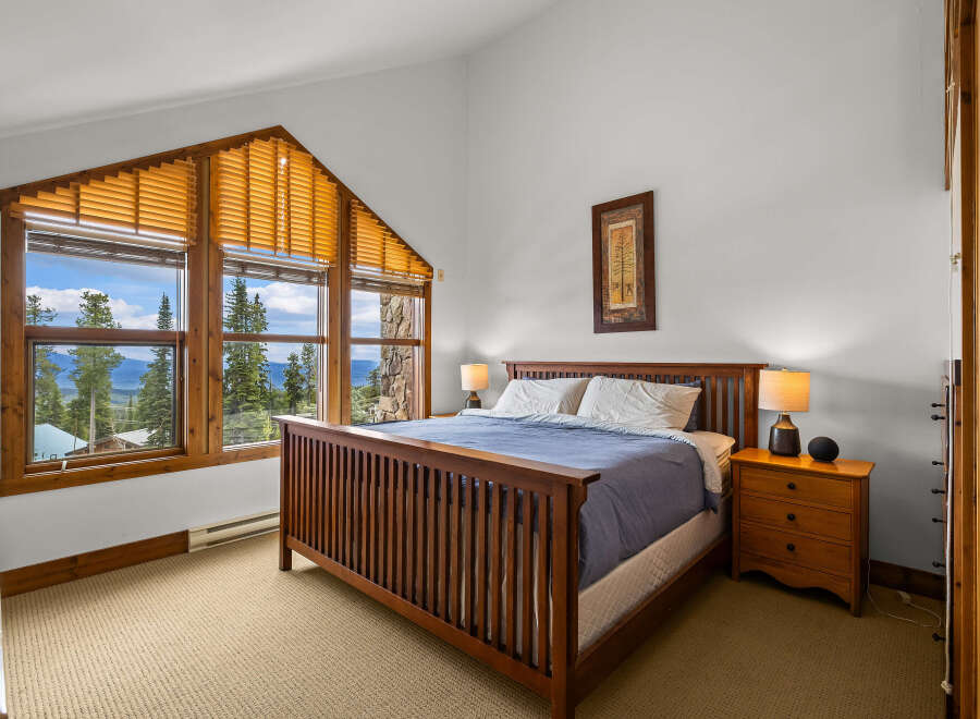 This stunning bedroom boasts a unique architectural design with a large, angled window offering breathtaking views of the surrounding landscape.