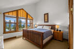 This stunning bedroom boasts a unique architectural design with a large, angled window offering breathtaking views of the surrounding landscape.