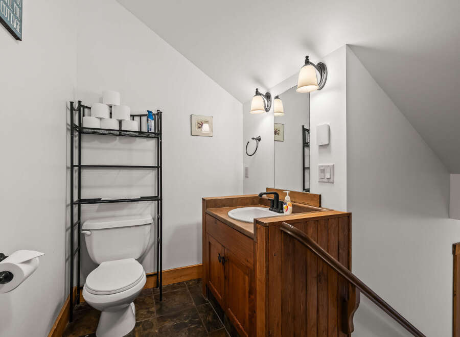 This charming bathroom features a rustic wooden vanity, a sleek black faucet, and a bright, well-lit mirror.