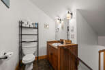 This charming bathroom features a rustic wooden vanity, a sleek black faucet, and a bright, well-lit mirror.
