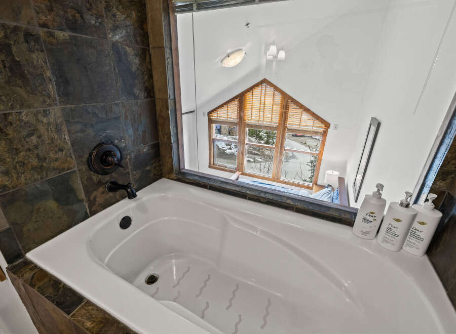 This luxurious bathroom features a stunning view through a large window, offering a serene escape.