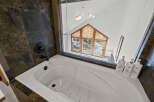 This luxurious bathroom features a stunning view through a large window, offering a serene escape.