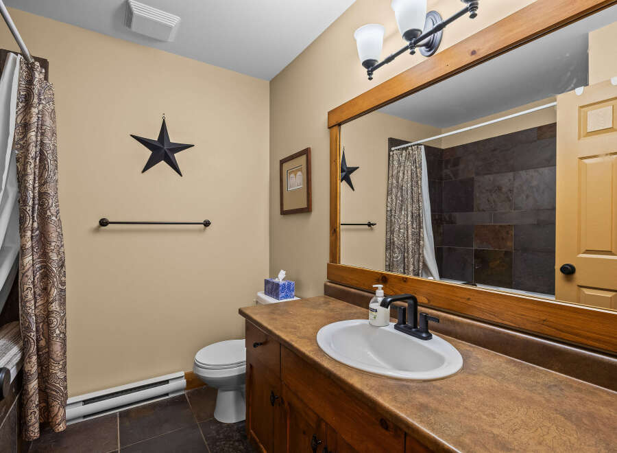 This charming bathroom features a rustic design with a wooden vanity and a stylish sink.