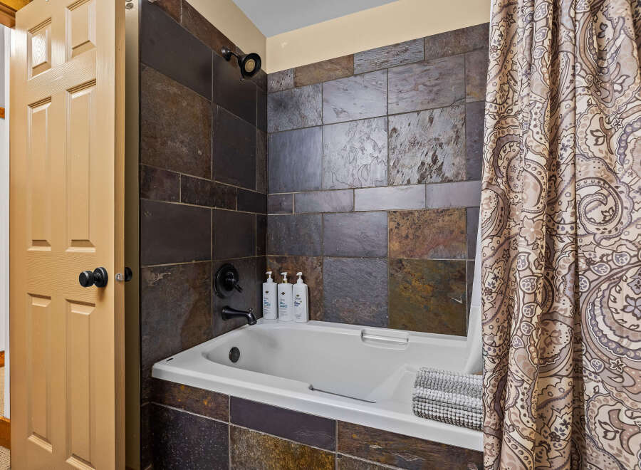 Step into a beautifully designed bathroom featuring a stylish tile shower and a relaxing bathtub.