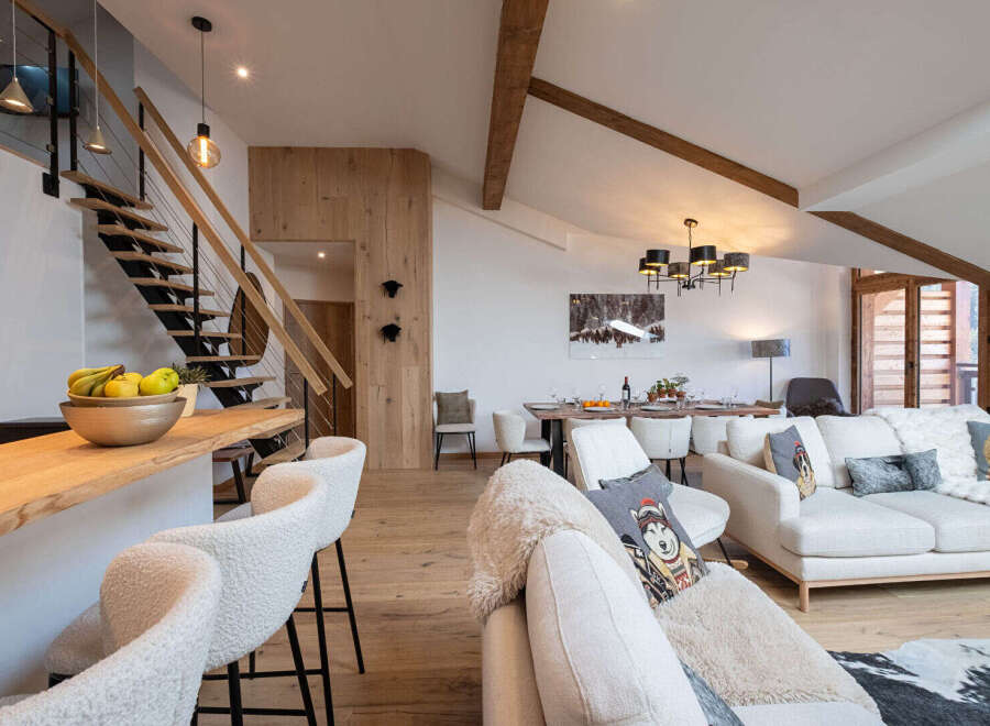 Experience luxury mountain living in this stunning open-concept space, featuring a modern staircase, a sleek kitchen island with bar seating, and a spacious living and dining area perfect for entertaining.