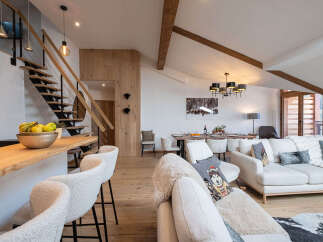 Experience luxury mountain living in this stunning open-concept space, featuring a modern staircase, a sleek kitchen island with bar seating, and a spacious living and dining area perfect for entertaining.