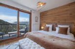 Experience breathtaking mountain views from this luxurious bedroom, featuring a spacious king-size bed with plush bedding and a cozy throw.