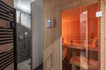 Experience ultimate relaxation in this modern spa area, featuring a sleek shower with geometric tilework and a luxurious, glass-enclosed sauna.